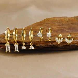 Detail of four-piece gold plated brass earring set with zircons on natural wood