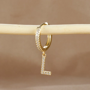 Detailed view of gold hoop earring with micro-paved zircon letter L on a branch