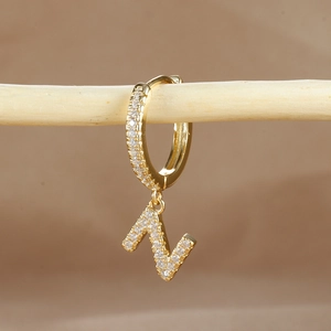 Detailed close-up of a gold-plated letter N huggie earring with micro-pave cubic zirconia