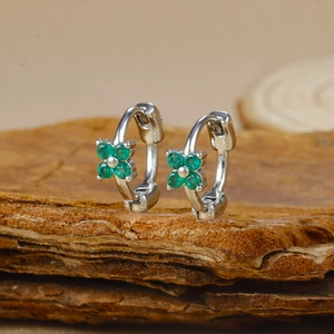 Macro shot of silver-plated geometric hoop earrings with four-leaf green zircon flowers