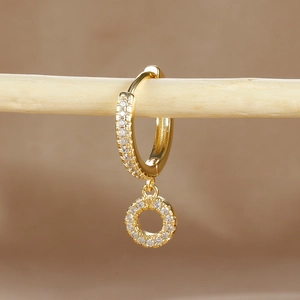 Close-up of gold-plated hoop earrings with micro-pave zircons on a wooden branch
