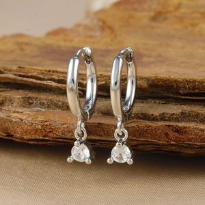 Macro shot of silver geometric brass earrings with round-cut zircon on a wooden stand