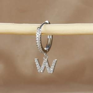 Macro detail of letter W earring with sparkling cubic zirconia on silver metal