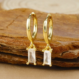 Detail of gold-plated geometric hoop earrings featuring a clear rectangular zircon drop
