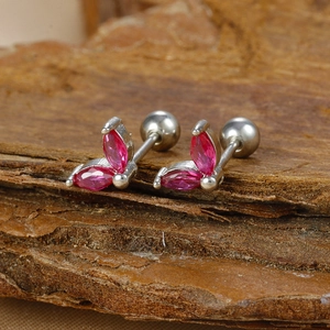 Macro shot of silver stud earrings with rose red marquise stones on natural bark