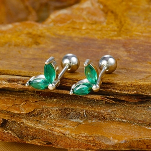 Macro shot of silver stud earrings with marquise-cut green gems on rustic bark surface