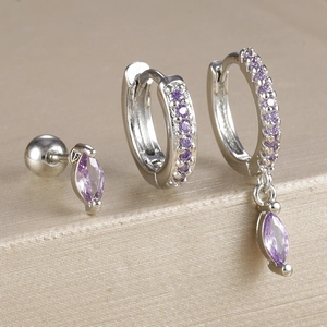 Détail macro d'un ensemble de trois boucles d'oreilles argentées avec zircons violets