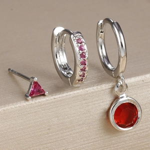 Macro detail of three-piece silver earring set with pink zircon and red gemstones