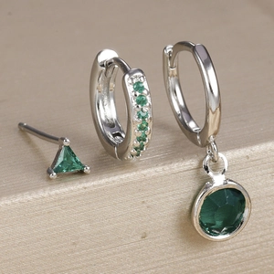 Close-up of three-piece silver earrings set with micro-pave green zircon and gemstones