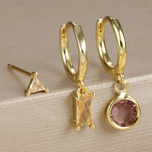Macro shot of gold geometric earrings set with yellow and red zircon stones