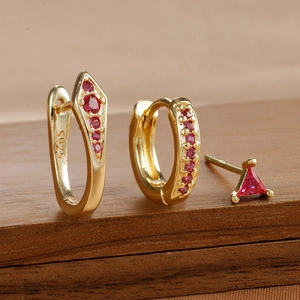Nahaufnahme von goldenen S925 Silberohrringen mit roten Zirkonia auf dunklem Holzgrund