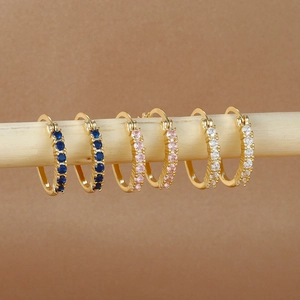 Detalle de tres pares de pendientes de aro dorados con cristales azules, rosas y blancos