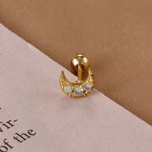 Detail of a golden crescent moon cartilage stud with three white zircons and screw ball back