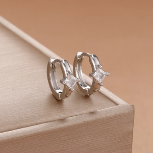 Detail view of silver sun hoop earrings with square zircon stone on jewelry box