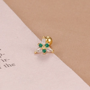 Dettaglio macro di un orecchino a fiore in oro con zircone verde e chiusura a sfera