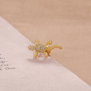 Detailed close-up of a gold-plated lizard stud earring with micro-set white cubic zirconia