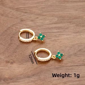 Détail de boucles d'oreilles trèfle à quatre feuilles dorées avec pierres vertes et diamants