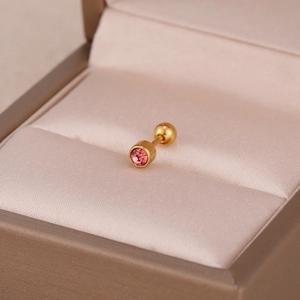 Vue macro d'un clou d'oreille en acier doré serti d'un oxyde de zirconium rose