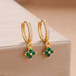 Vue détaillée de boucles d'oreilles trèfle dorées avec pierres vertes et zircon