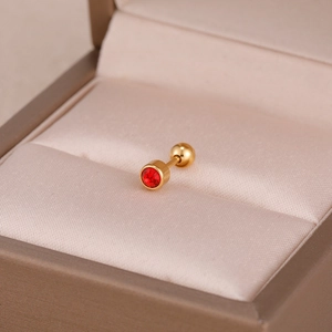 Vue macro d'un clou d'oreille en acier doré avec zircon rouge et fermoir à vis