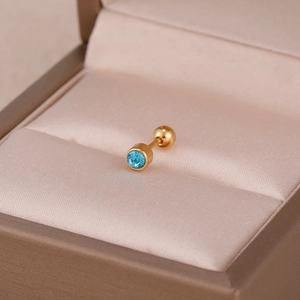 Macro d'une boucle d'oreille en acier doré avec un zircon bleu clair rond serti