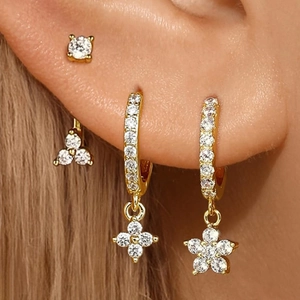 Parure boucles d'oreilles trèfle doré et clous en cristal portés par un mannequin