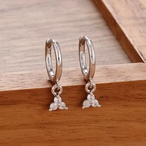 Detail of s925 silver hoop earrings with three zircon triangle drop on a wooden stand