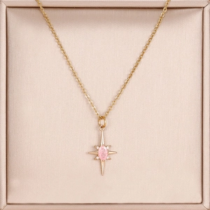 Dettaglio del ciondolo a stella in oro 14K con zircone rosa in un portagioie di seta