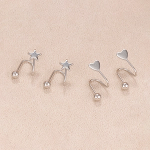 Macro shot of silver star and heart spiral stud earrings with minimalist metal luster