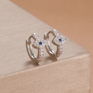 Macro shot of silver evil eye hoop earrings with blue zircon and pavé crystal details