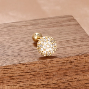 Détail macro de boucle d'oreille dorée avec pavage de zircones et fermoir à vis sur bois
