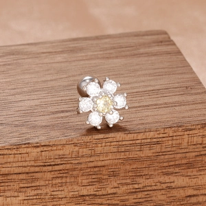 Gros plan de boucles d'oreilles fleur en argent et pierres sur support en bois