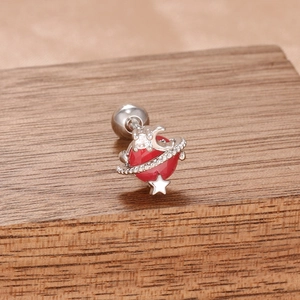 Détail de la boucle d'oreille Saturne avec opale rouge sur surface en bois texturé