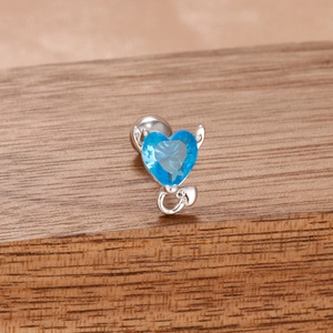 Détail macro des boucles d'oreilles cœur en pierre bleue avec accents de cornes de diable