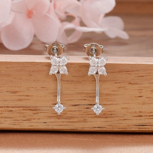 Primer plano de pendientes de flor con circonitas plateadas y colgante en fondo floral suave