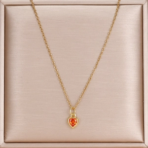 Detailansicht goldene Halskette mit herzförmigem orangefarbenem Edelsteinanhänger an feiner Kette