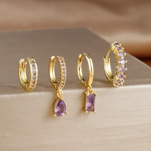 Detail view of four-piece gold earring set with rectangle and drop purple zircons