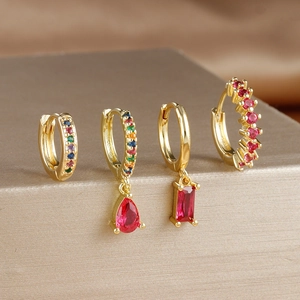 Macro view of four gold-plated earrings with red zircons and rectangle pendants