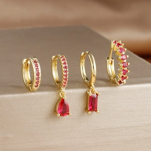 Detailed view of four gold-plated earrings set with radiant red faceted gemstones