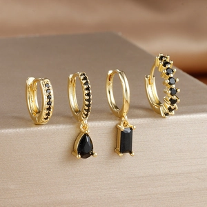 Macro detail of four gold earrings set with black zircons on a metallic display stand