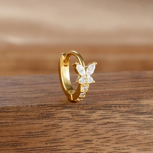 Detailed view of butterfly gold earring with marquise cubic zirconia on wood