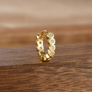 Macro shot of gold micro-pave small hoop earrings with cubic zirconia on wood