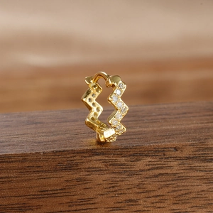Macro shot of gold-plated zigzag hoop earrings with cubic zirconia on wood
