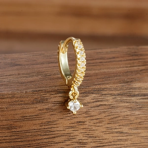 Macro detail of gold hoop earrings with small round-cut cubic zirconia dangling pendant