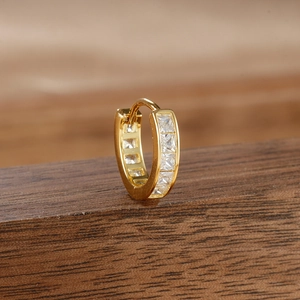 Macro shot of gold-plated hoop earrings with channel-set square zirconia on wood