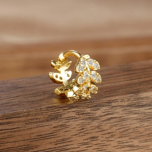 Macro detail of gold-plated leaf hoop earrings with shimmering clear zircon inlays