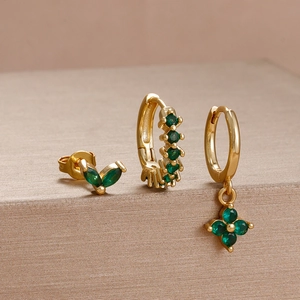 Close-up of gold flower earrings set with vibrant green marquise and round zircon stones