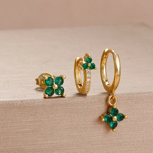 Detail of gold flower earrings set with emerald zircon stones on metallic stand