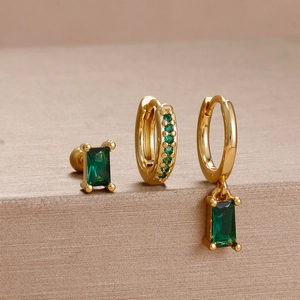 Detailed macro view of vintage gold earrings set with emerald green rectangular gemstones