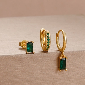 Macro detail of emerald green gemstones set in elegant gold hoop and stud earrings